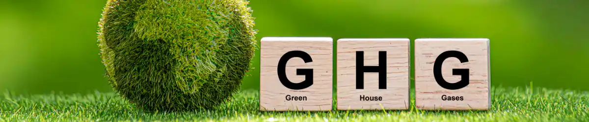 芝生の上に木製ブロックで『G』『H』『G』と書かれた立方体が並び、それぞれにGreen、House、Gasesの文字が添えられている。温室効果ガス（GHG）を表すイメージ画像